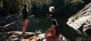 Three women jumping into a natural pool