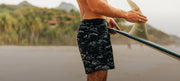 Man on beach wearing NHM print board shorts