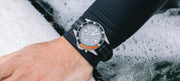 Man wearing Finisterre + Timex watch whilst putting on a wetsuit